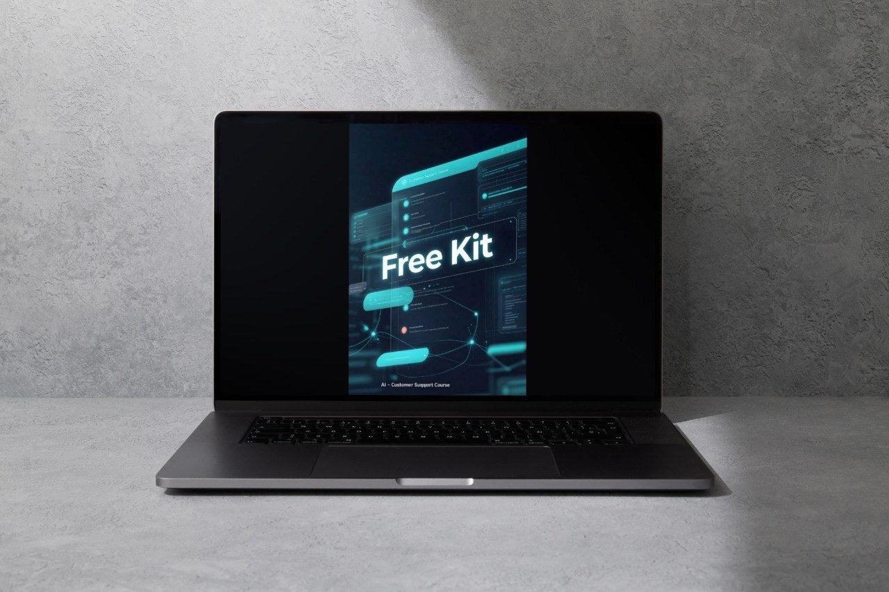A dark gray laptop sits open on a light gray surface against a textured gray wall, with its screen displaying a digital graphic that reads 'Free Kit'.